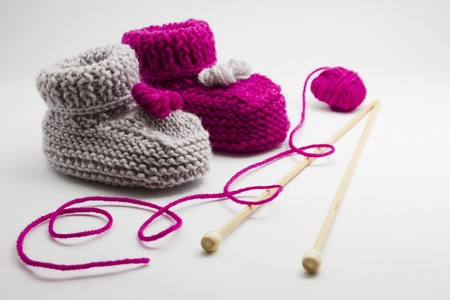 Couple knitted bootees to newborn, knitting needles and balls of yarn isolated on white background. Hand-made socks for the baby.の写真素材