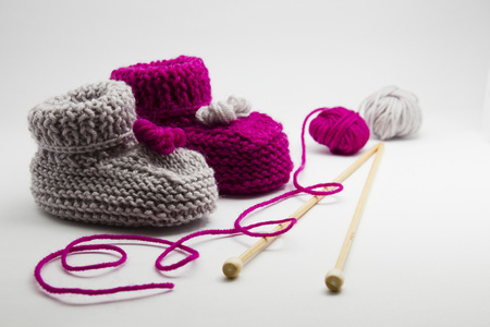 Couple knitted bootees to newborn, knitting needles and balls of yarn isolated on white background. Hand-made socks for the baby.の写真素材
