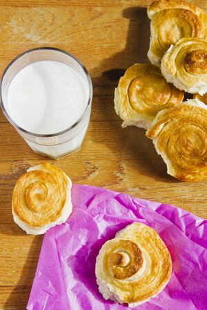 Breakfast with cinnamon buns and glass of milk on wooden table. Homemade baking.の写真素材