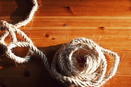 Vintage toned image of hank large ship's rope on the background of a brown wooden table. Frame made of rope.の写真素材
