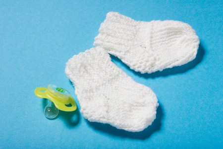 Knitted by hands wool white hat and socks for the newborn. Winter hand made clothing for the child on blue paper background. Hobbies for Women: knitting.の写真素材