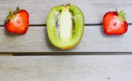 Still life with a kiwi and strawberry on a white wooden table. Natural fruit farm.の写真素材