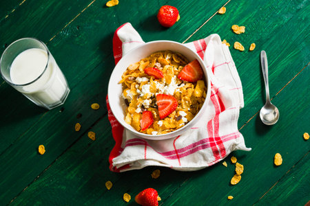 Breakfast of oatmeal and corn flakes with milk and strawberries. Still life in a rustic style with a...