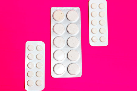 Three packs of pills lying on the pink background. Treatment of diseases pharmaceuticals.