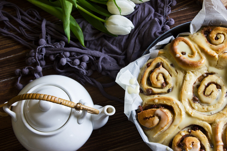 American cinnamon rolls sinabon made at home, lying on a brown wooden table. Homemade cakes with icing.の写真素材
