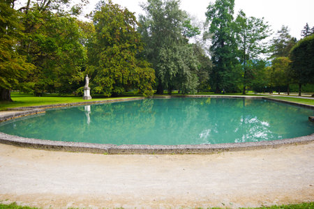 Big pond with azure water in the park of the palace Hellbrunn in Salzburg, Austria. Artificial...