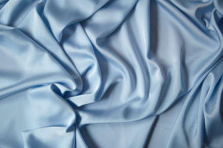 Beautiful draped silk fabric in blue. Background from the waves of satin fabricの写真素材