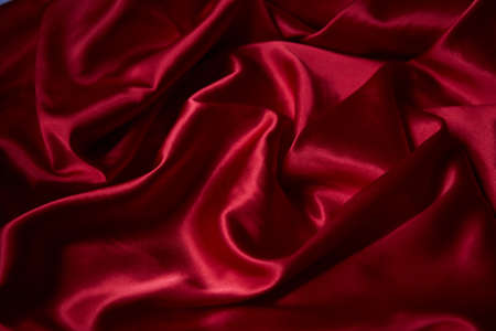Beautiful draped silk fabric in red. Background from the waves of satin fabricの写真素材