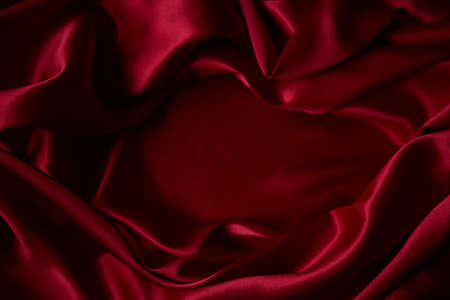 Beautiful draped silk fabric in red. Background from the waves of satin fabricの写真素材