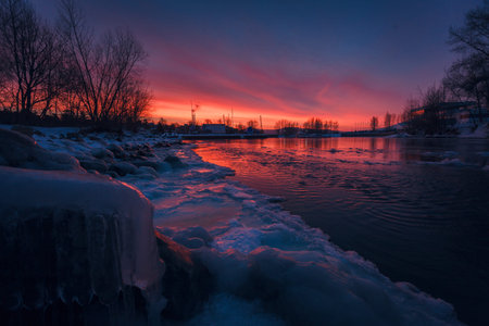 Winter Sunset on the river Volga. Icy rocks near the water