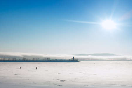 Fishermen walk on the frozen water In the background is a scene of a fogの写真素材