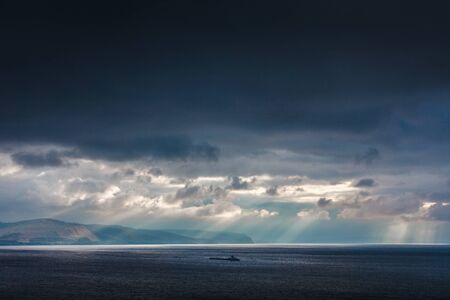 Mountains in the rays breaking through the clouds the sunの写真素材