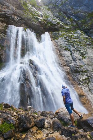 A man poses in front of waterfall in Abhazia. High in the mountainsの写真素材