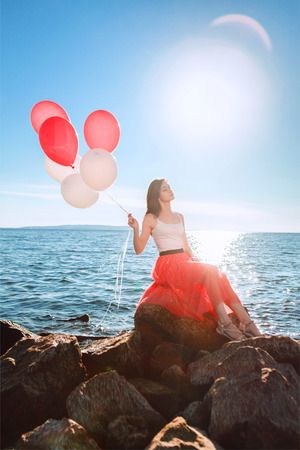 Pretty girl with many colored balloons in handの写真素材