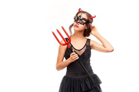 Portrait of beautiful she-devil posing with trident on Halloween against white backgroundの写真素材