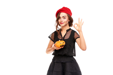 Studio portrait of young woman in Halloween costume posing with jack-o-lanternの写真素材