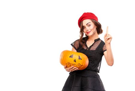 Studio portrait of young woman in Halloween costume posing with jack-o-lanternの写真素材