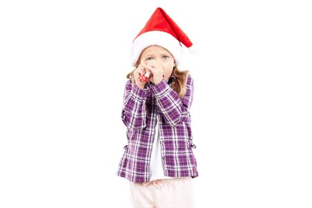Portrait of sweet little girl in Santa hat blowing into party blowerの写真素材