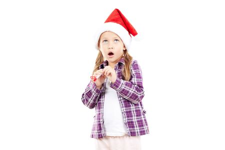 Portrait of sweet little girl in Santa hat blowing into party blowerの写真素材