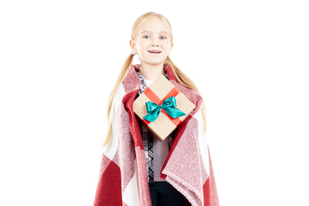 Studio portrait of little girl wrapped in blanket holding Christmas gift boxの写真素材
