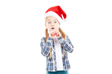 Portrait of sweet little girl in Santa hat blowing into party blowerの写真素材
