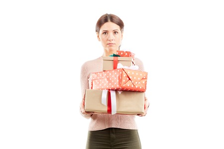 Portrait of young woman holding stack of Christmas giftsの写真素材