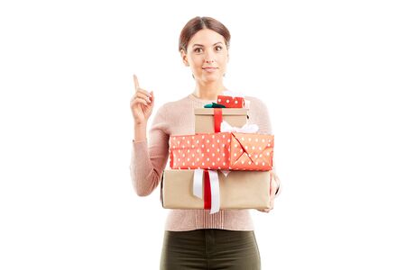 Portrait of young woman holding stack of Christmas giftsの写真素材