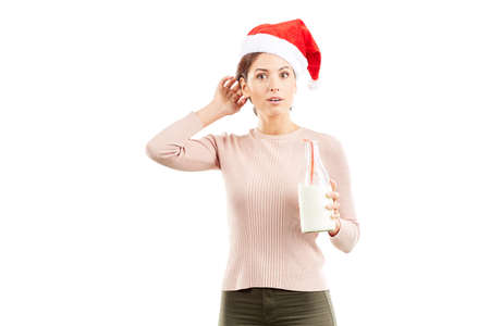 Portrait of woman in Santa hat holding bottle of milk on white backgroundの写真素材