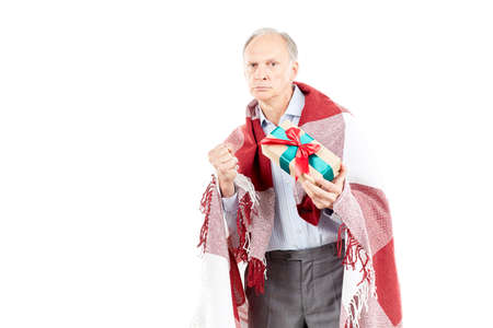 Portrait of senior man wrapped in blanket holding Christmas giftの写真素材