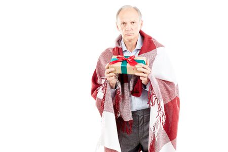 Portrait of senior man wrapped in blanket holding Christmas giftの写真素材