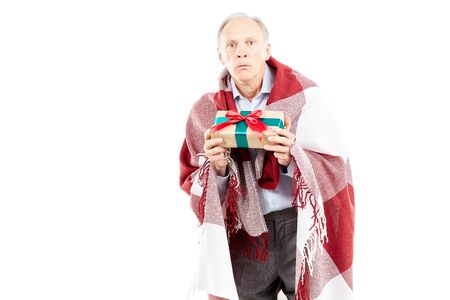Portrait of senior man wrapped in blanket holding Christmas giftの写真素材