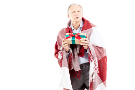 Portrait of senior man wrapped in blanket holding Christmas giftの写真素材