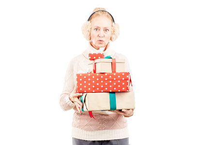 Portrait of senior woman in earmuffs holding heap of Christmas gifts