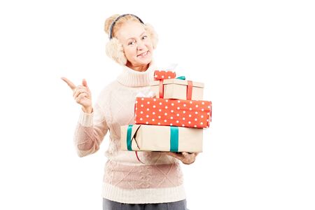 Portrait of senior woman in earmuffs holding heap of Christmas giftsの写真素材