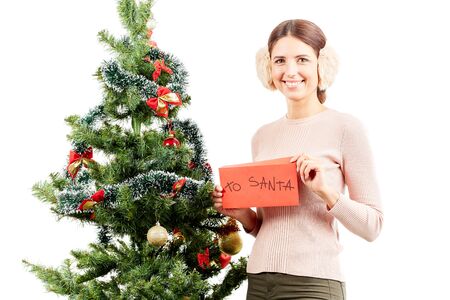 Portrait of beautiful woman in earmuffs posing near Christmas treeの写真素材