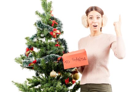 Portrait of beautiful woman in earmuffs posing near Christmas treeの写真素材