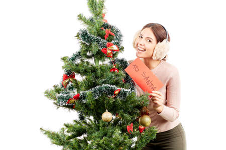 Portrait of beautiful woman in earmuffs posing near Christmas treeの写真素材