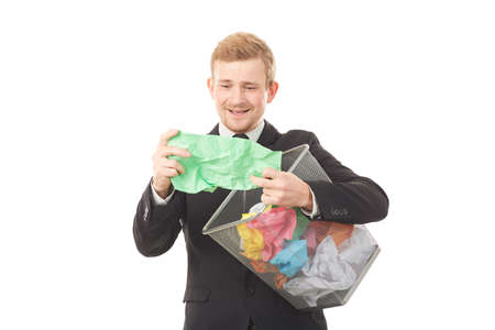 Portrait of businessman searching document in paper basket among crumpled papersの写真素材
