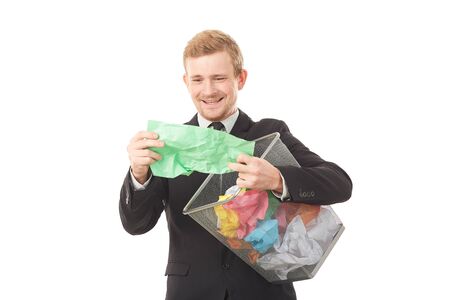 Portrait of businessman searching document in paper basket among crumpled papersの写真素材