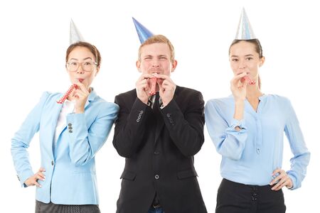 Portrait of office workers wearing party hats and blowing into party horn blowersの写真素材