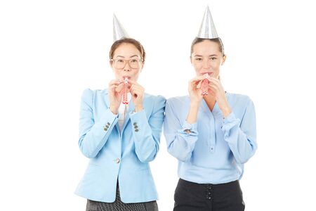 Portrait of office workers wearing party hats and blowing into party horn blowersの写真素材