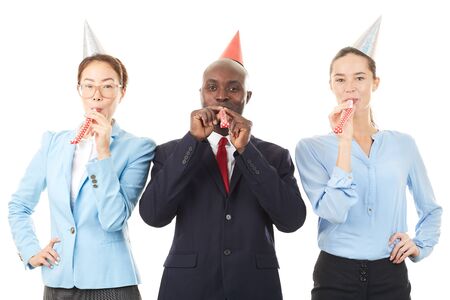 Portrait of office workers wearing party hats and blowing into party horn blowersの写真素材