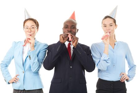 Portrait of office workers wearing party hats and blowing into party horn blowersの写真素材