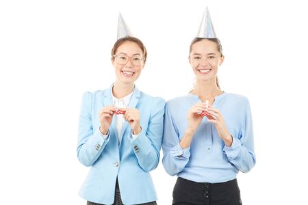Portrait of office workers wearing party hats and blowing into party horn blowersの写真素材