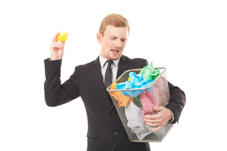 Portrait of businessman searching document in paper basket among crumpled papers