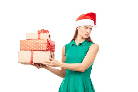 Portrait of young womanin Santa hat holding stack of Christmas gifts on white backgroundの写真素材