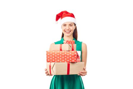Portrait of young womanin Santa hat holding stack of Christmas gifts on white backgroundの写真素材
