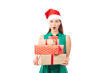Portrait of young womanin Santa hat holding stack of Christmas gifts on white backgroundの写真素材
