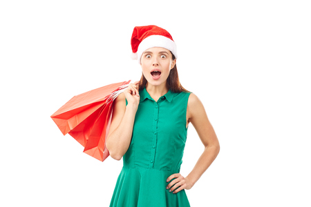 Studio portrait of young woman in Santa hat posing with shopping bags on white backgroundの写真素材