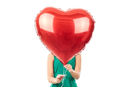 Young woman holding big heart shaped balloon on white backgroundの写真素材